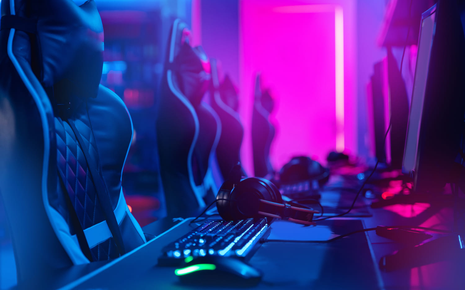 Een gaming setup met neonverlichting toont professionele esportsuitrusting met headsets en toetsenborden, klaar voor competitieve actie.